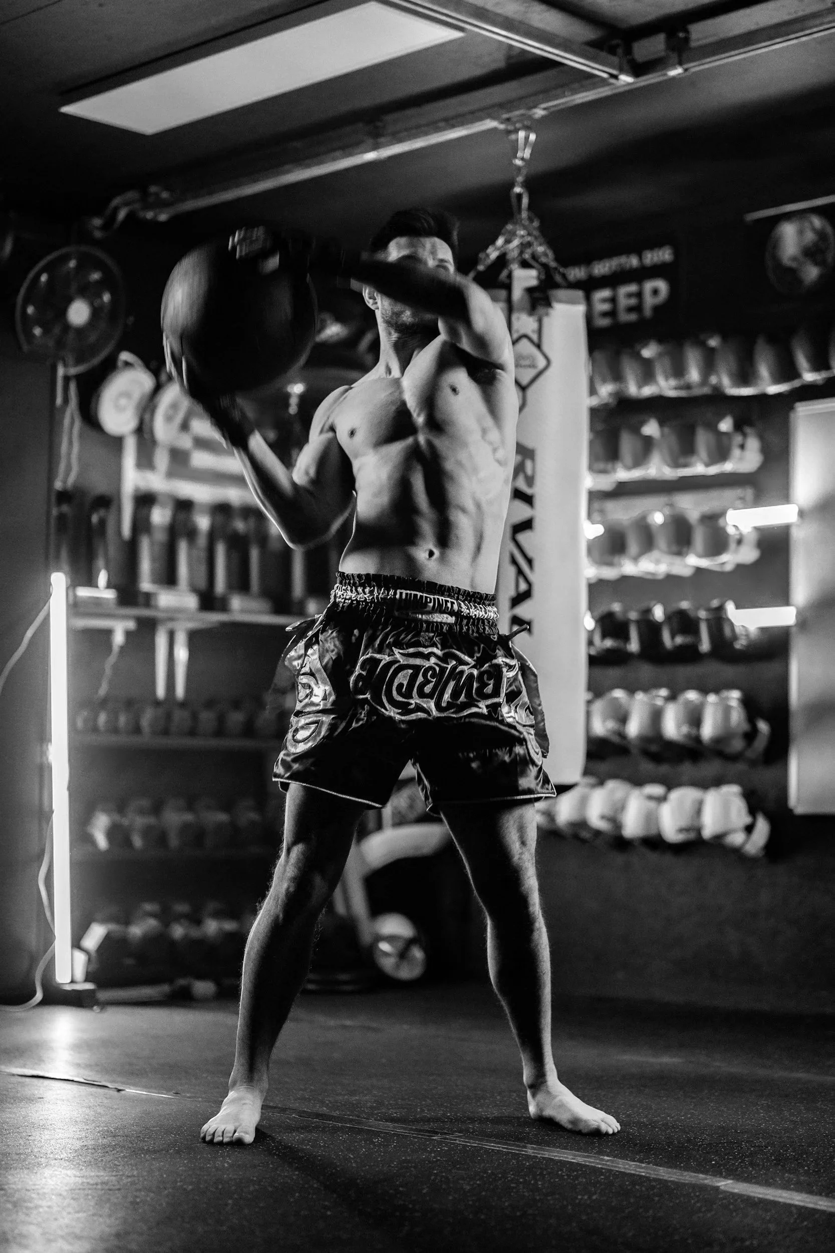 Man performing a med ball slam in boxing gym black and white