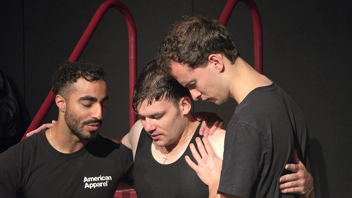 Three young adult men praying after baptism