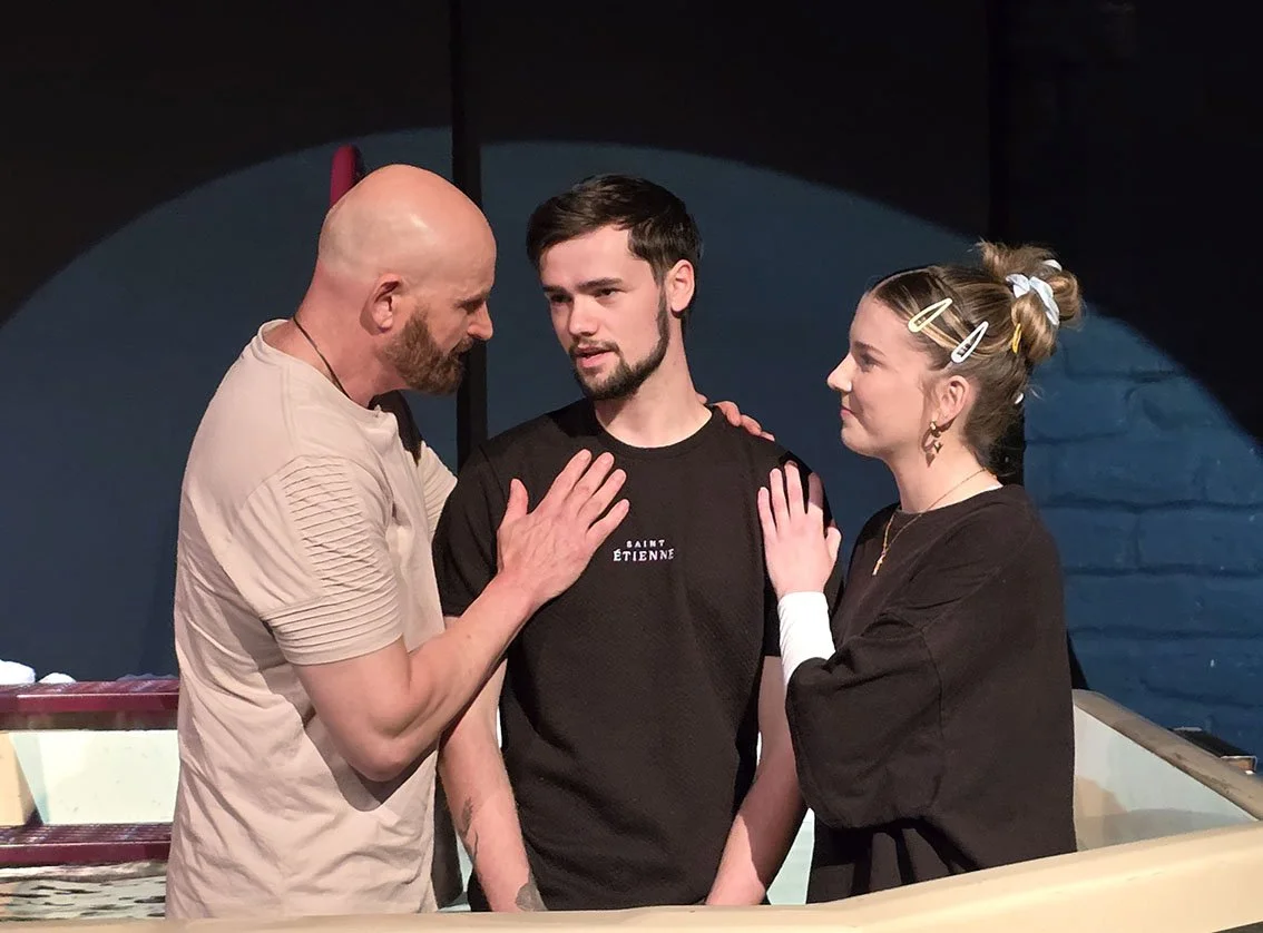 Man in his fifties, young lady in her twenties praying for a young man 