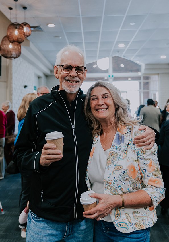 Husband and wife in their sixties hugging with big smiles