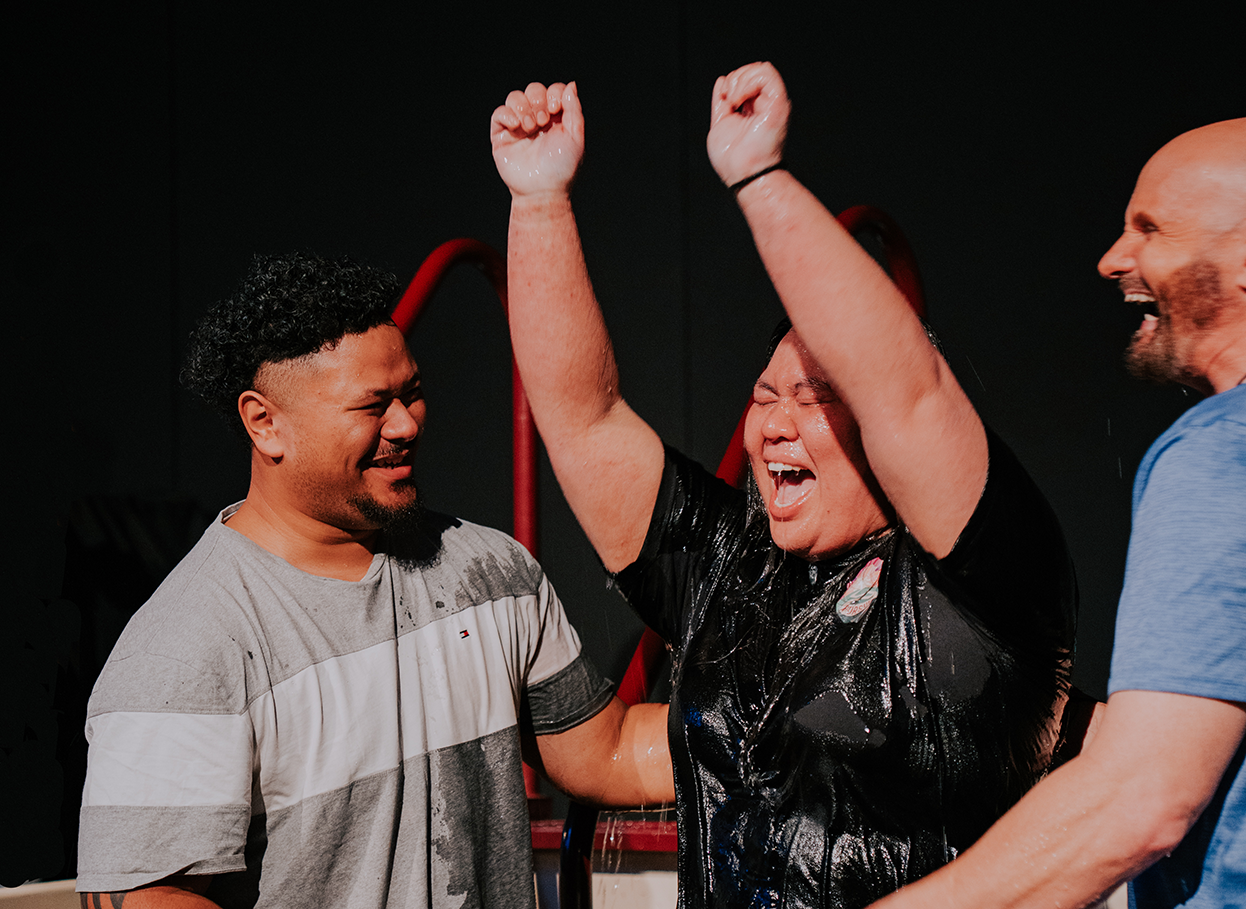 Young lady getting baptised coming up out the water with her hands in the air