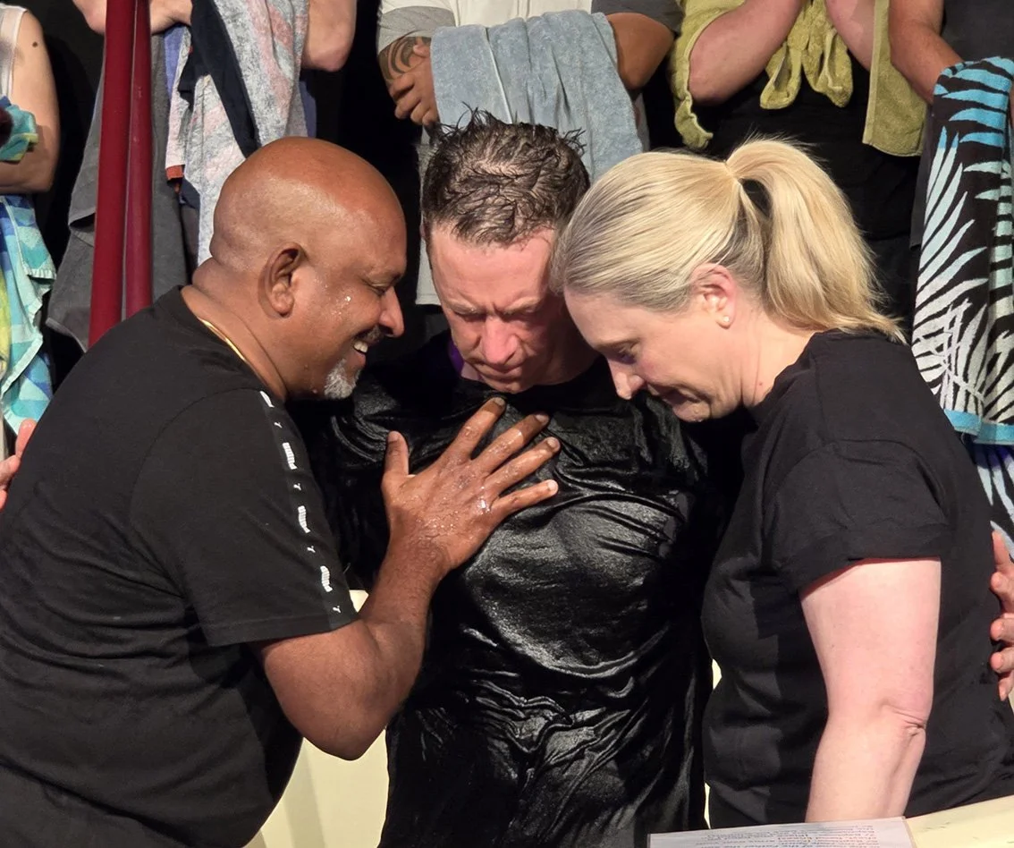 Three adults praying in the baptistry for a man
