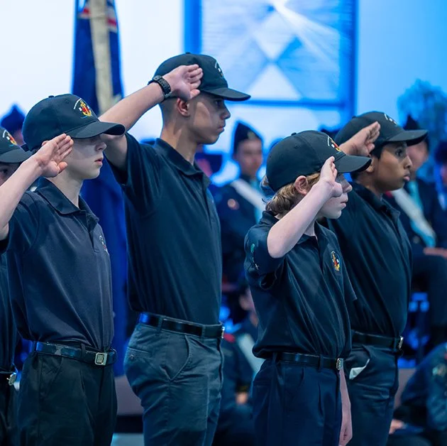 Four boys in uniform saluting