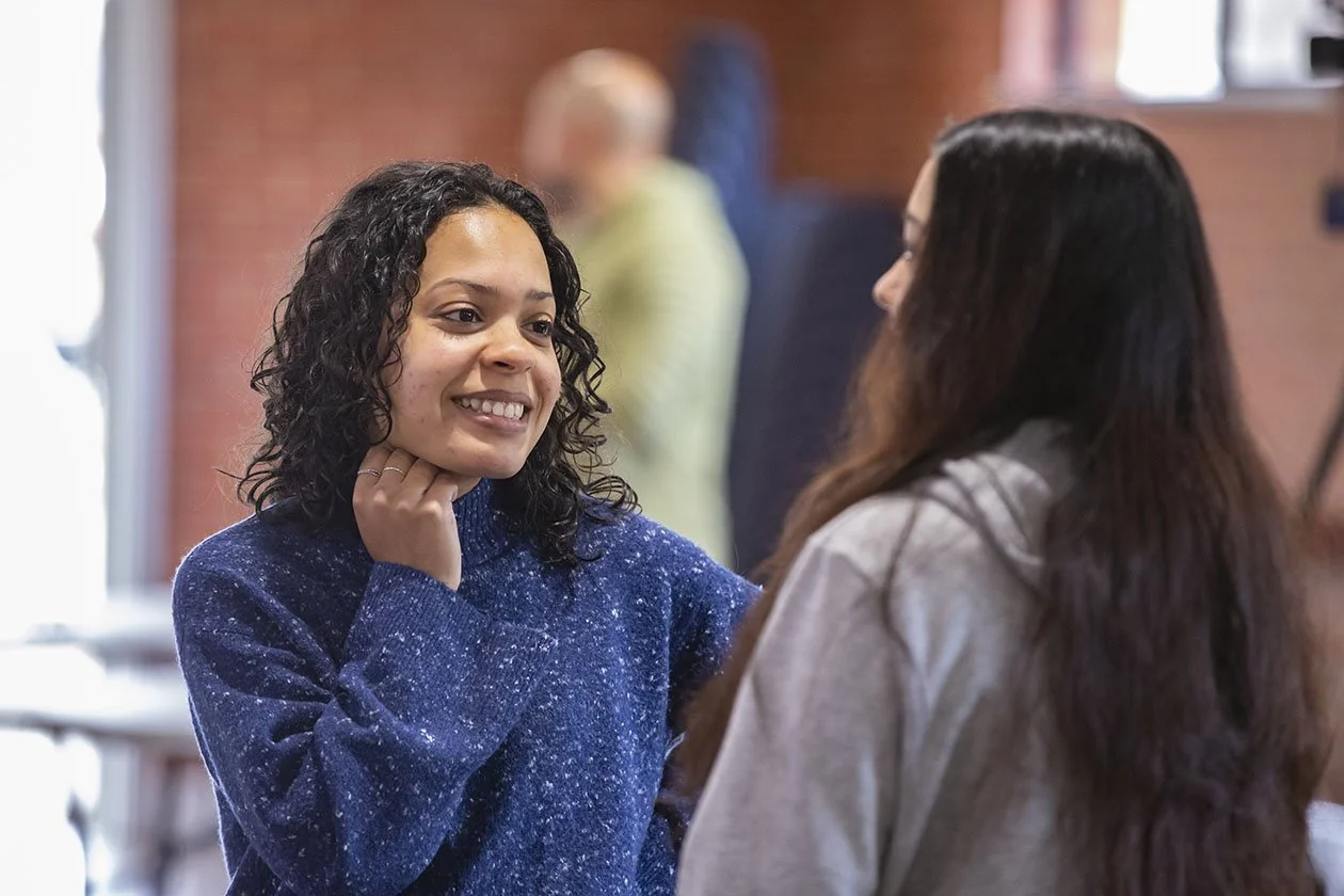 Two young ladies talking wearing jumpers and long hair