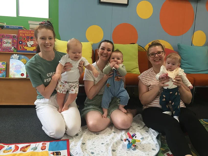 Three happy mums on the floor at playgroup with their babies