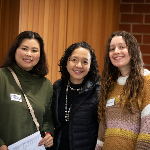 Three ladies all wearing casual clothes standing inside