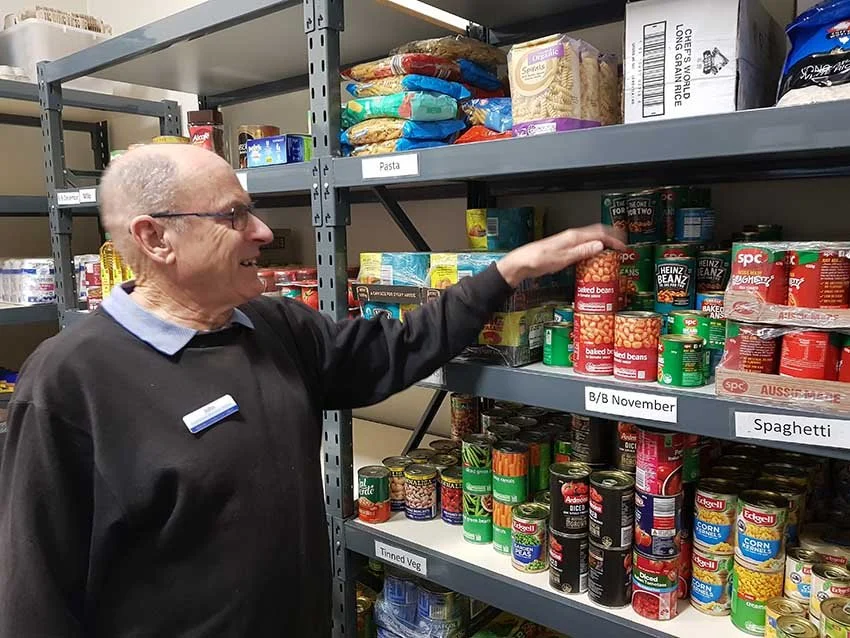 Volunteer stacking shelf of cans