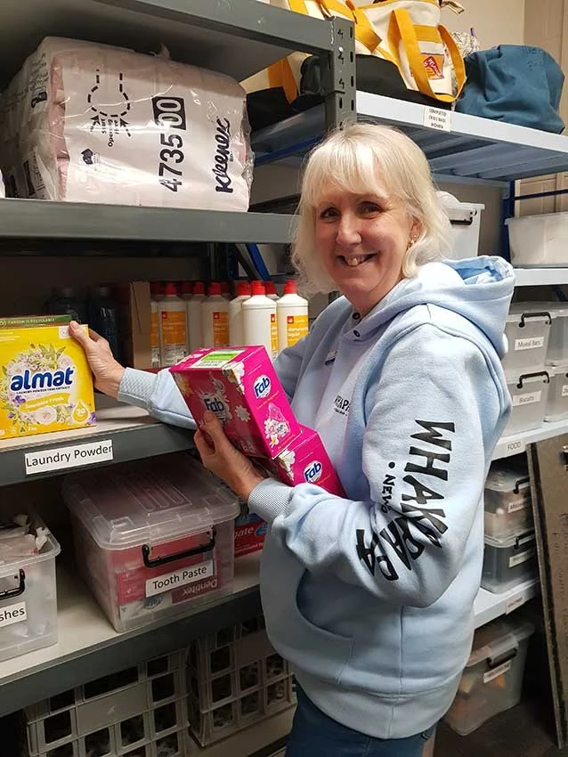 Volunteer lady putting laundry powder on shelf
