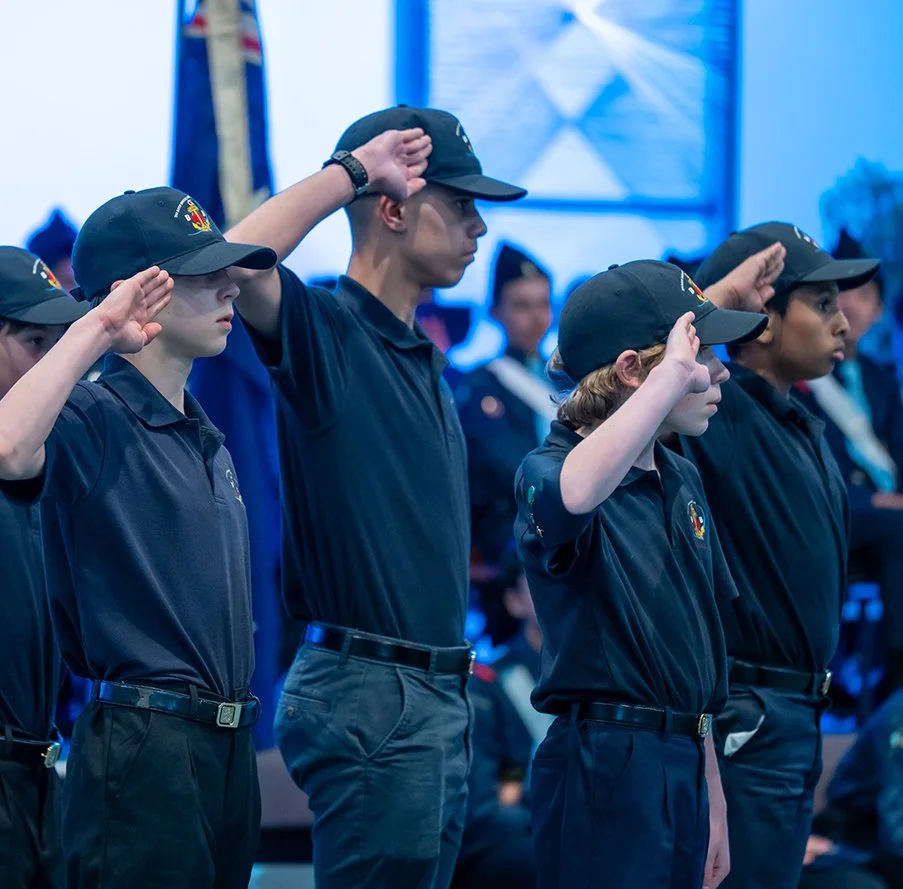 Four young boys wearing blue Boys Brigade uniforms with hats saluting