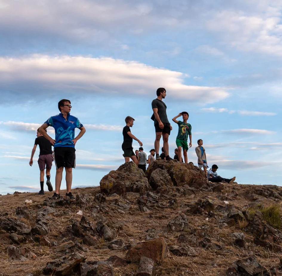 Image of boys standing on a dirt mound looking out the the sky