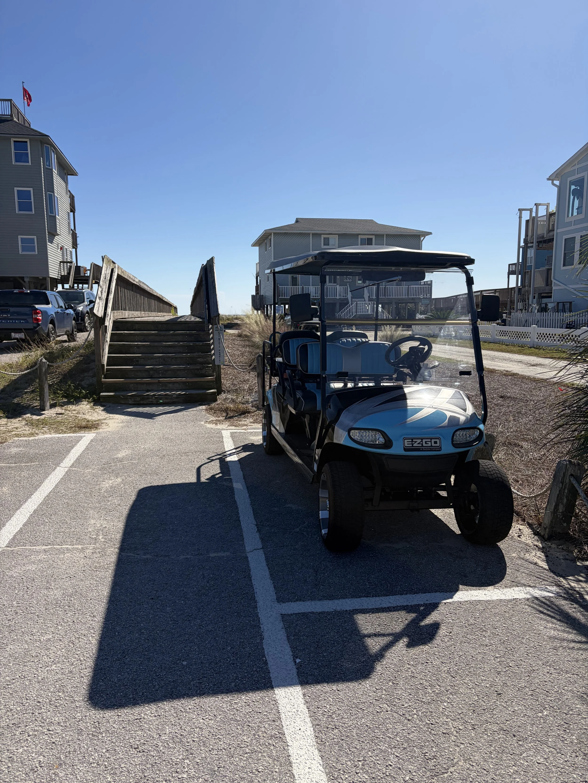 Golf cart parked beside the beach access stairs near Isle Be There in Emerald Isle, NC