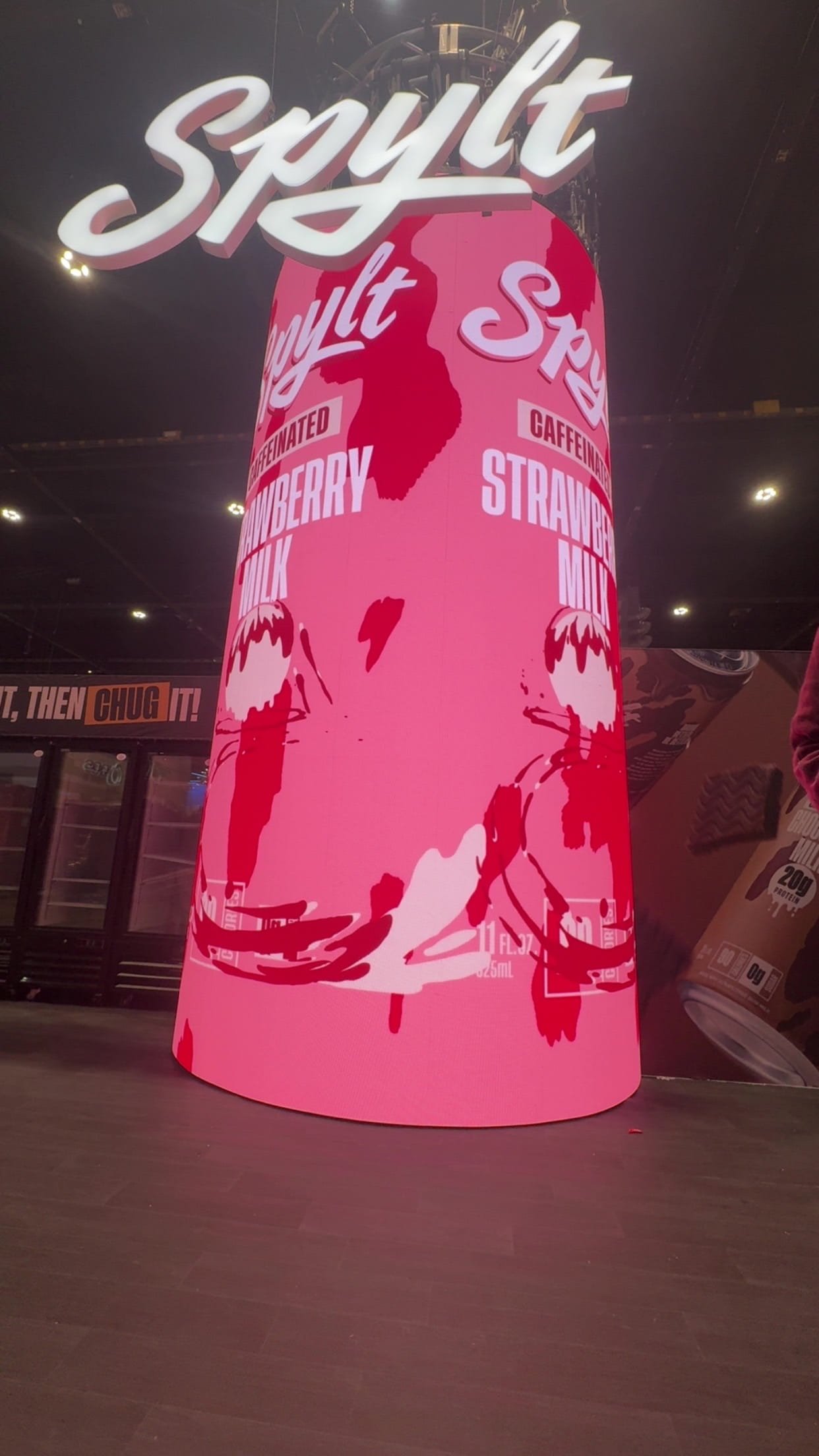 A large pink cylindrical display with the word 'Sprite' in white cursive above it. The display features flavors such as strawberry, cherry, and milk, with illustrations of strawberries and cherries.