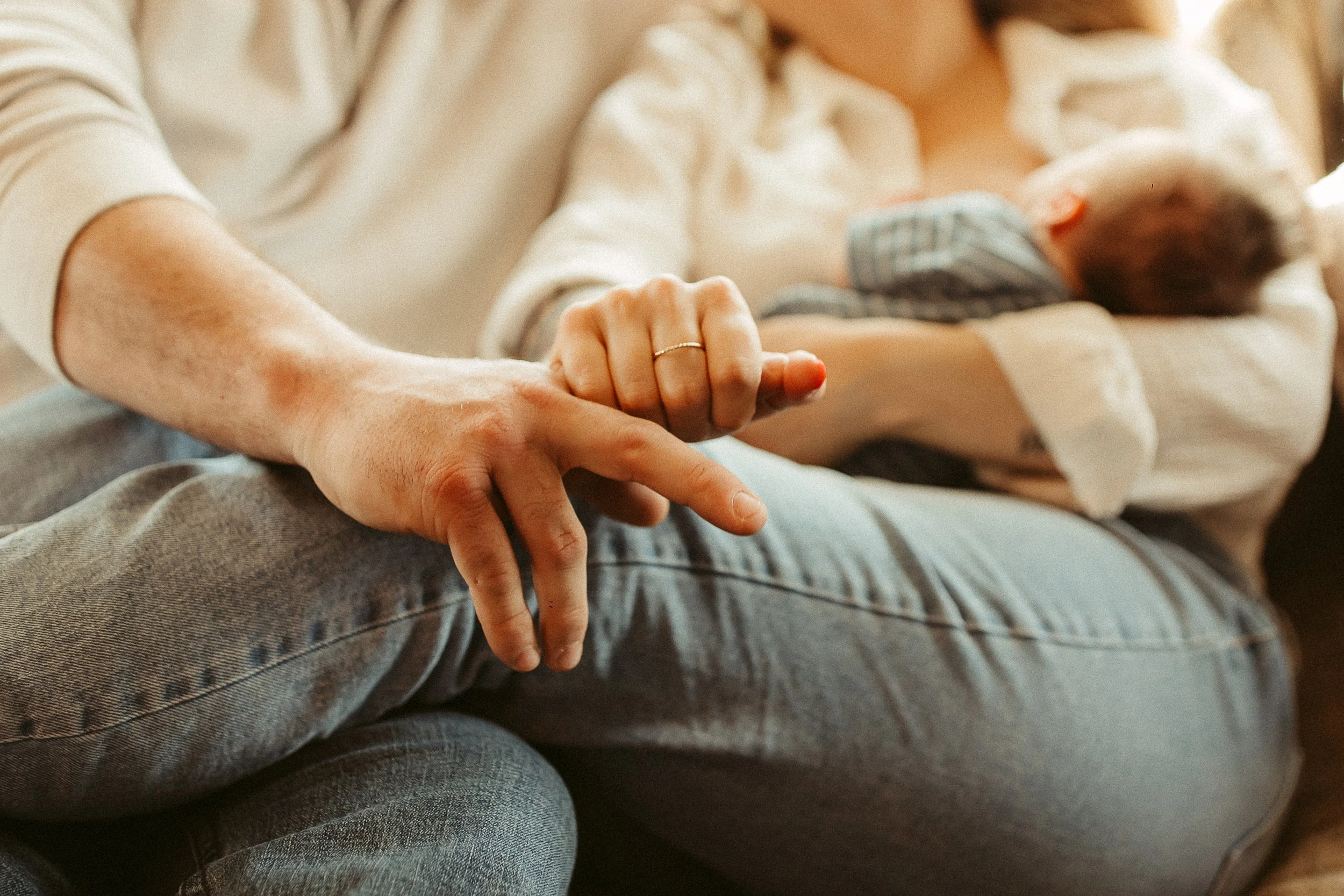 Close-up of an older woman holding a newborn baby in her arms, with her hand gently resting on her knee.