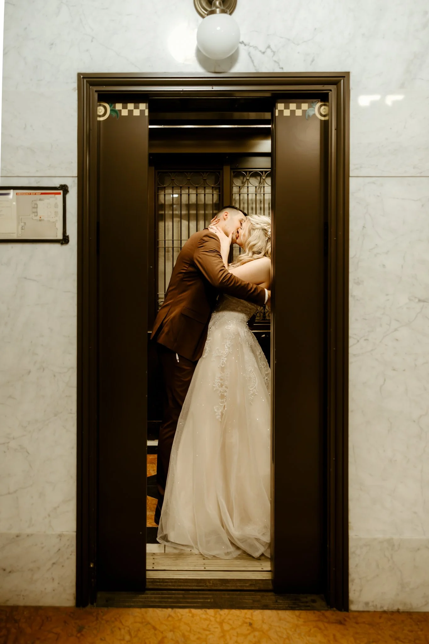 A bride and groom kissing inside a vintage elevator.