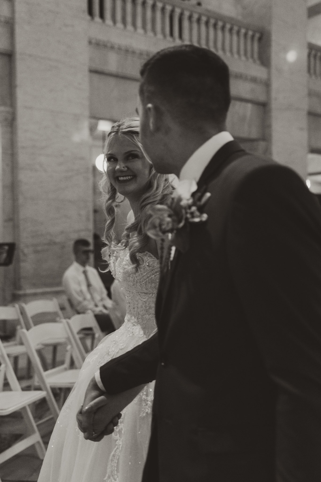 A bride and groom holding hands and looking at each other inside a church during their wedding ceremony.