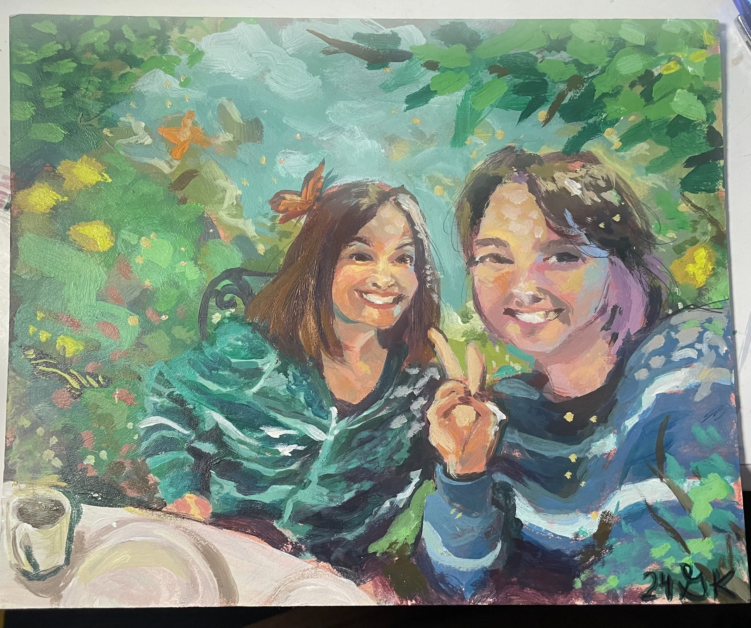 A colorful painting of two smiling women sitting together outdoors near a garden with lots of greenery and butterflies. One woman is making a peace sign with her hand. There are cups and a plate on a table in front of them.
