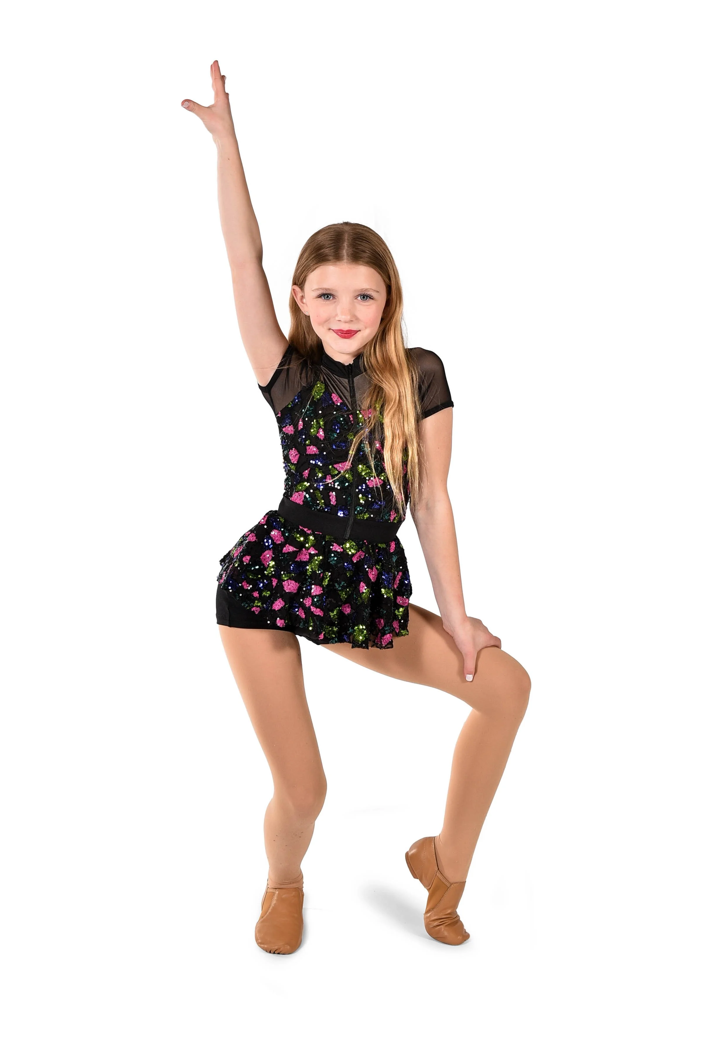 Young girl in black sequined figure skating dress and tan figure skates performing a pose against a white background.