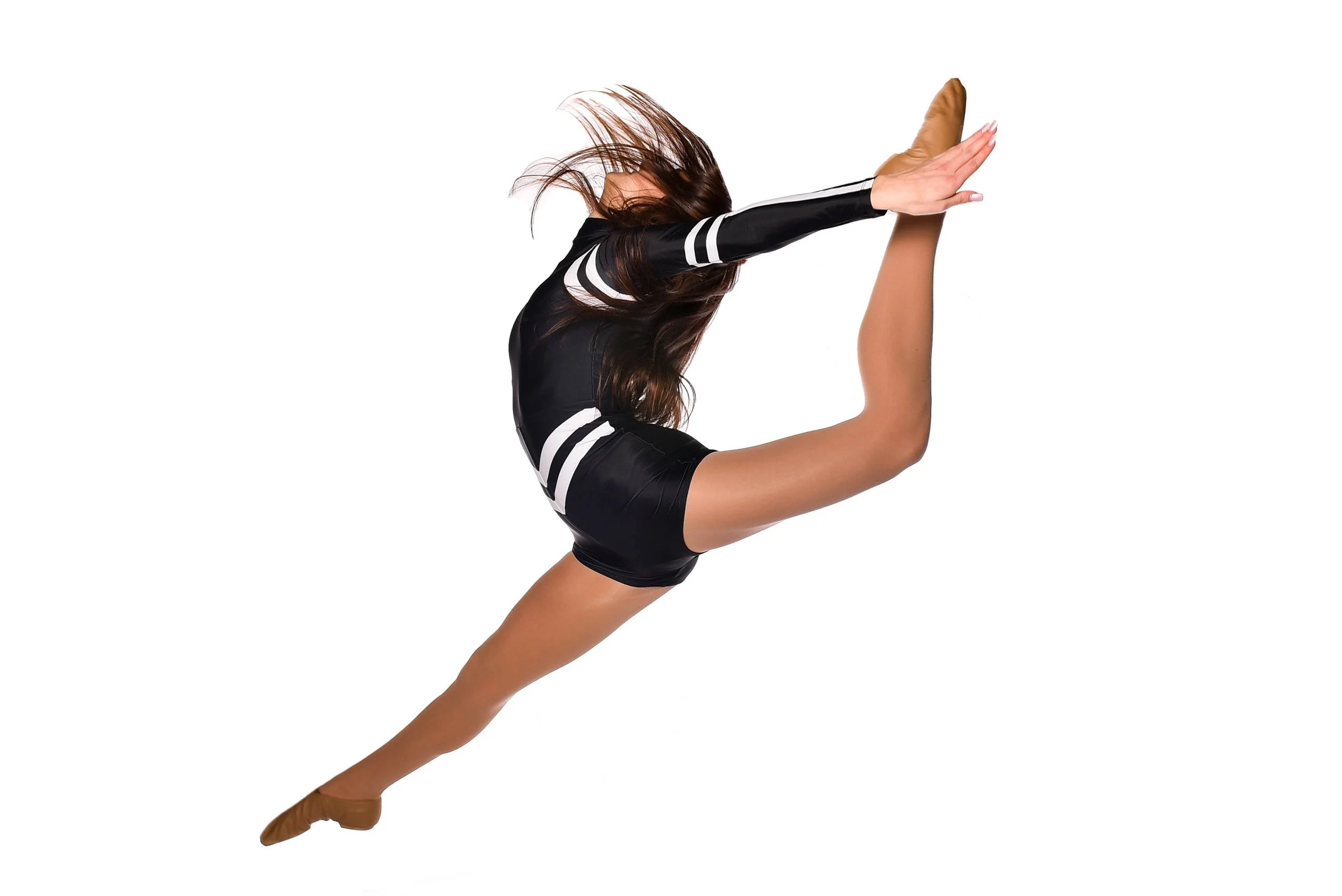 A female dancer in a black and white uniform performing a split leap with one leg extended forward and the other backward, arms raised, hair flowing, against a plain white background.