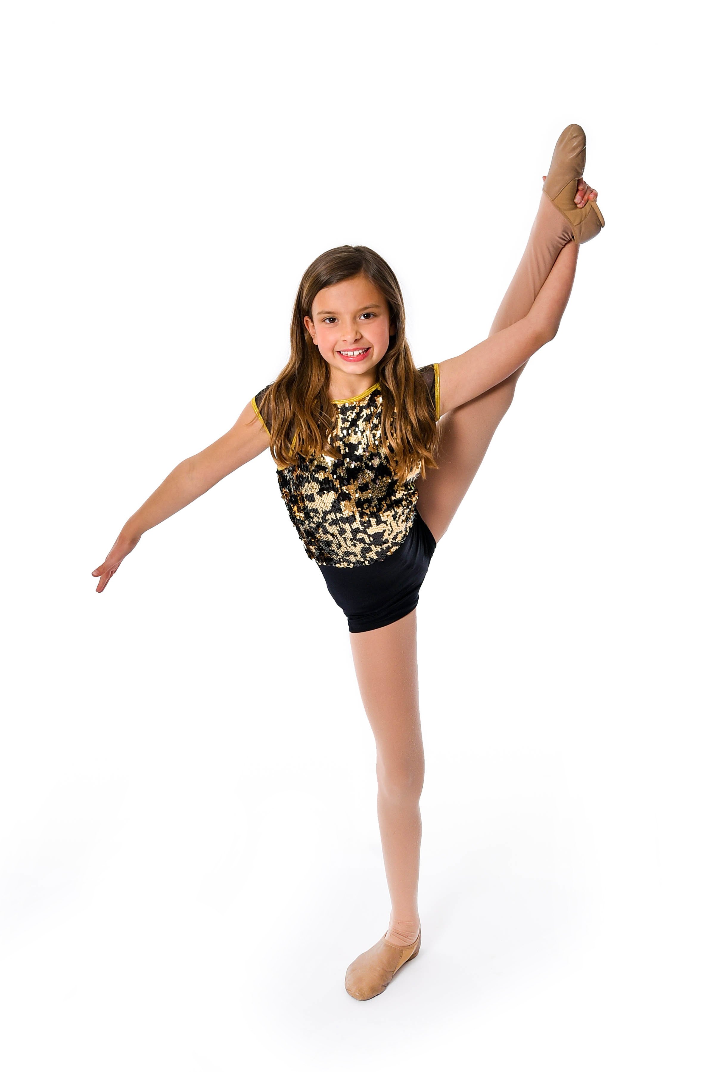 Young girl in dance costume performing an arabesque pose onstage.