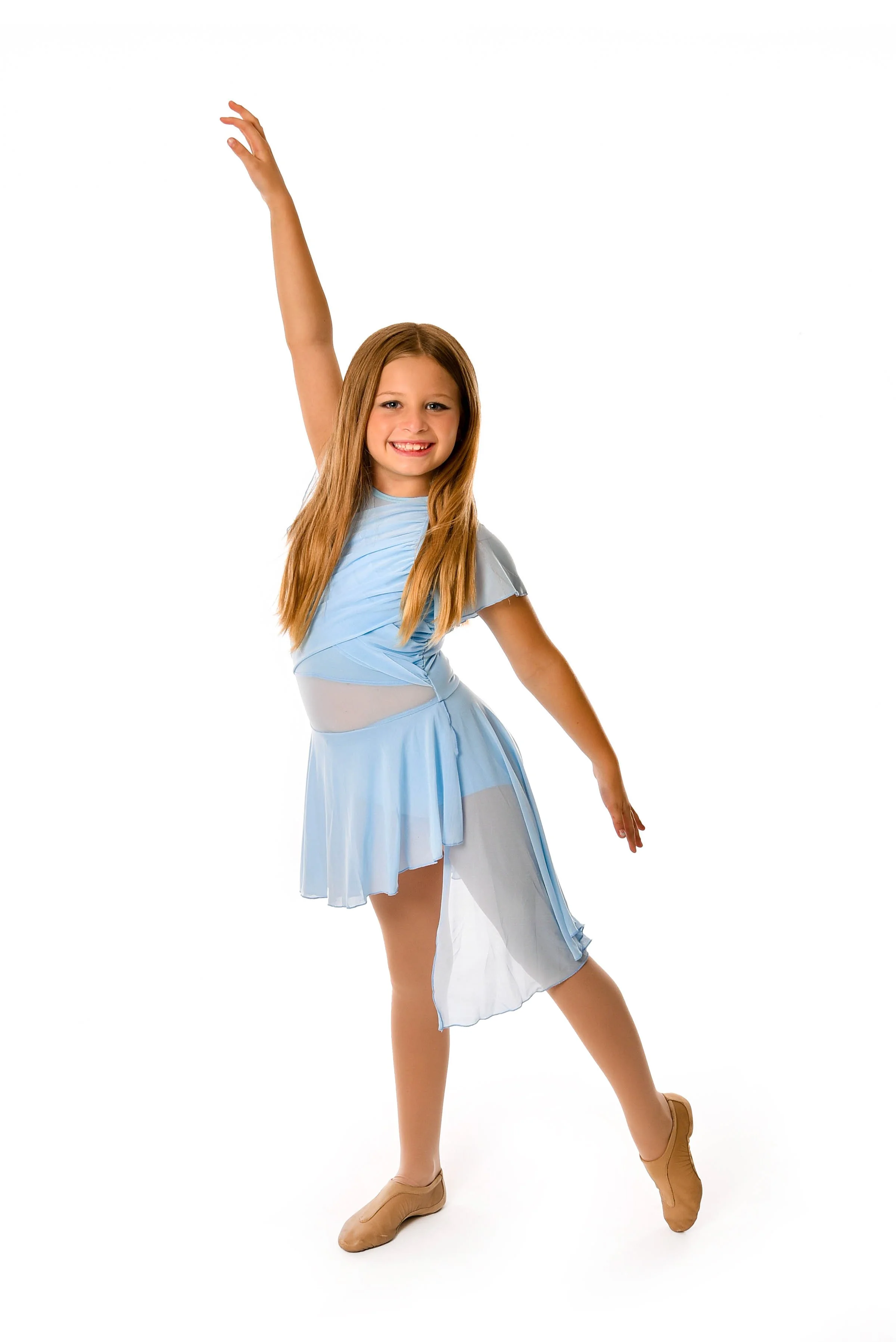 Young girl dancing in a light blue dress and tan dance shoes, smiling with one arm raised and the other extended to the side.