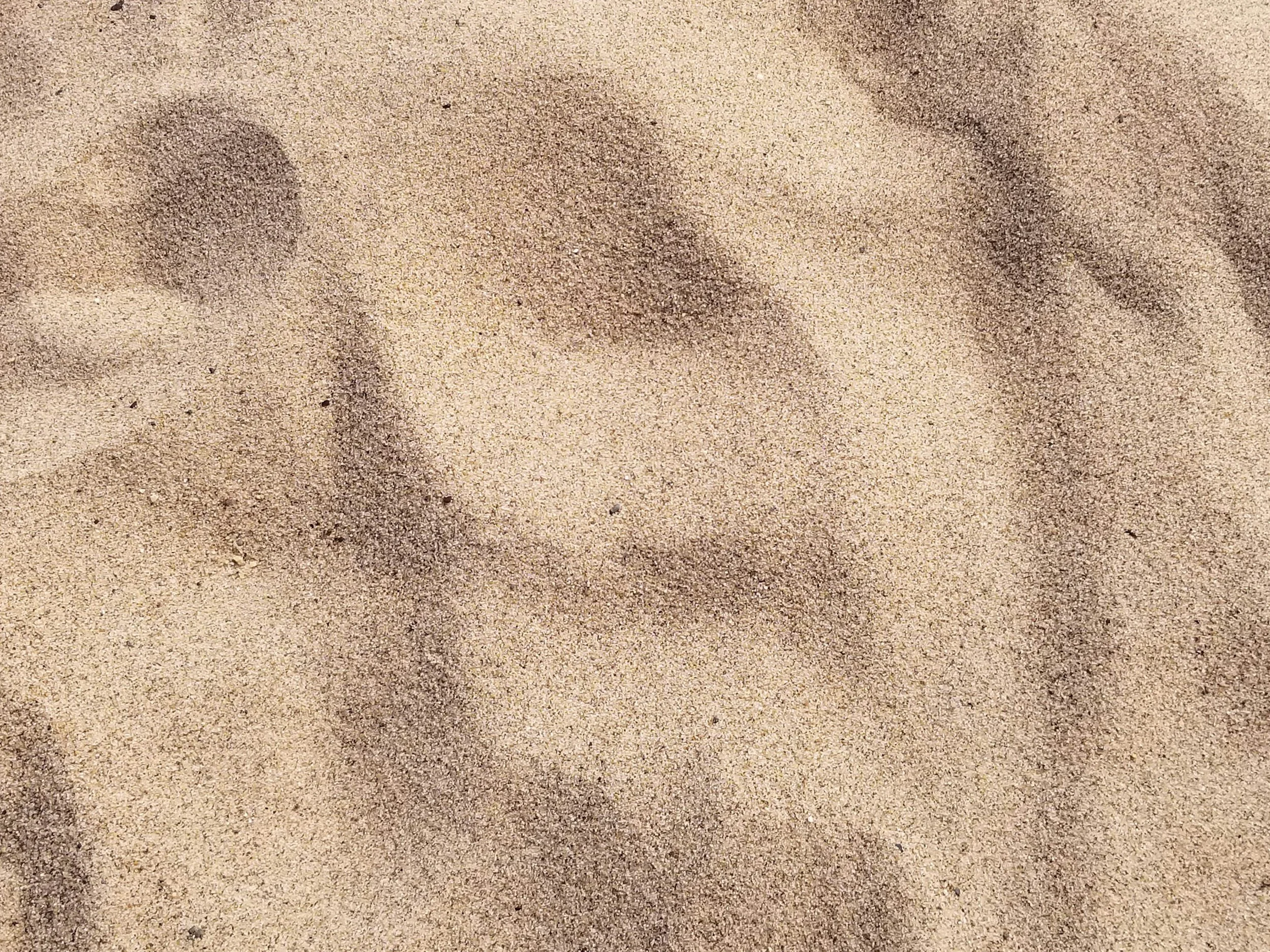 Footprints in sandy beach or desert surface.