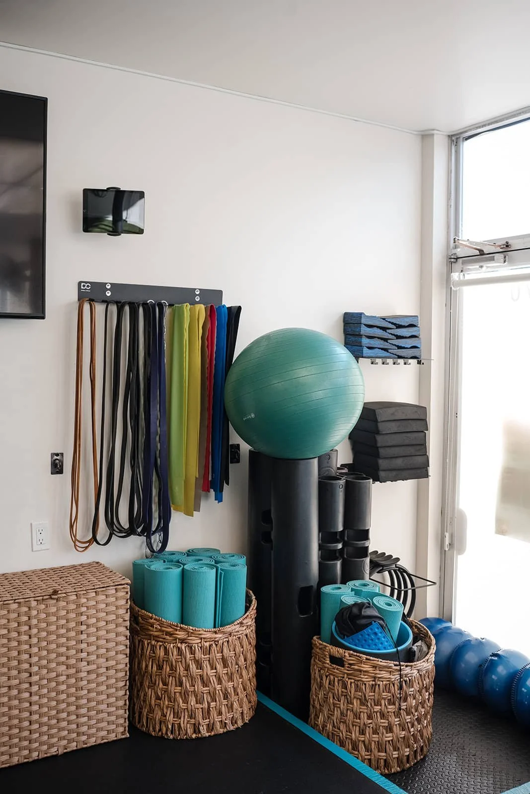 Fitness studio corner with exercise mats, foam rollers, resistance bands, stability balls, and step platforms.