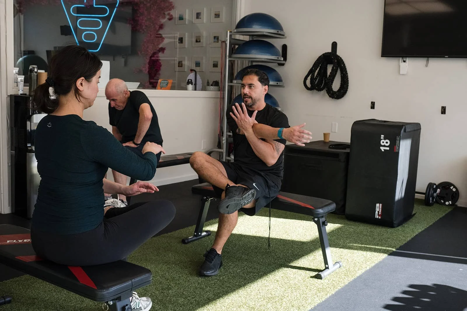 A fitness trainer demonstrates a stretch to a client.