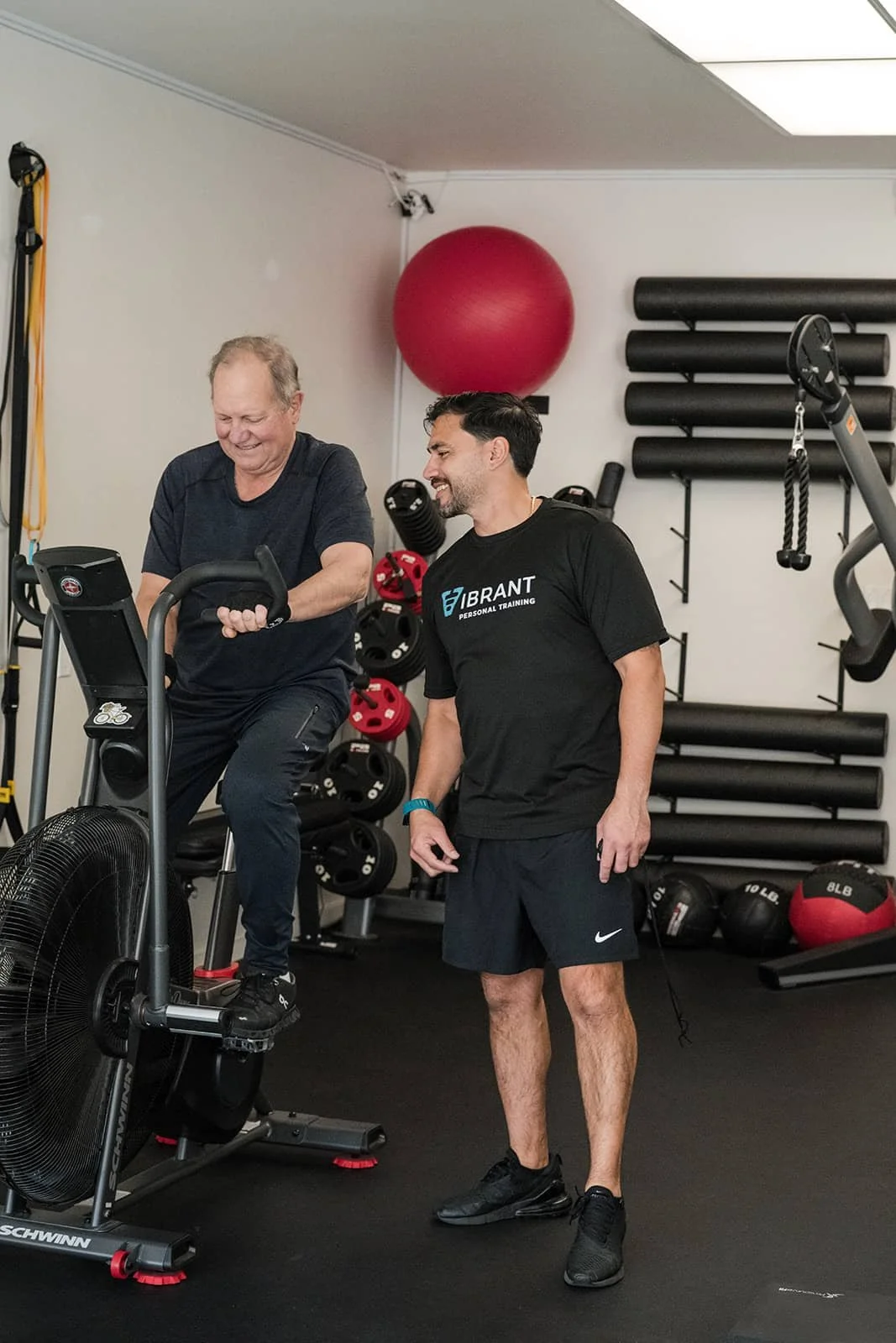 Personal Training session with one man on an exercise bike, and the other standing nearby instructing.
