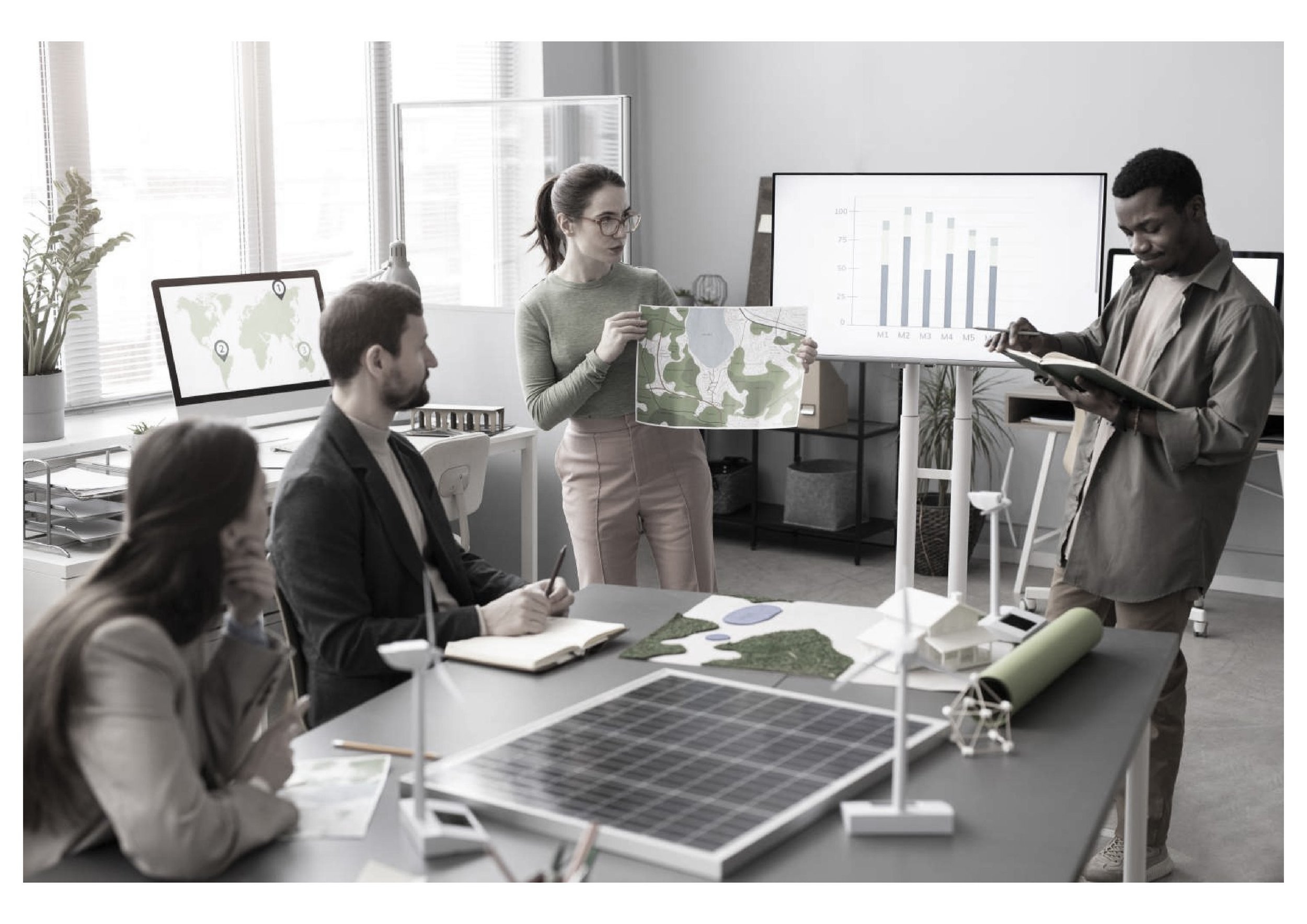 A group of five professionals in a modern office discussing urban planning. One woman is presenting a large map while the others are seated around a table with architectural models, a solar panel, and documents. Two screens display a world map with location markers and a bar chart.