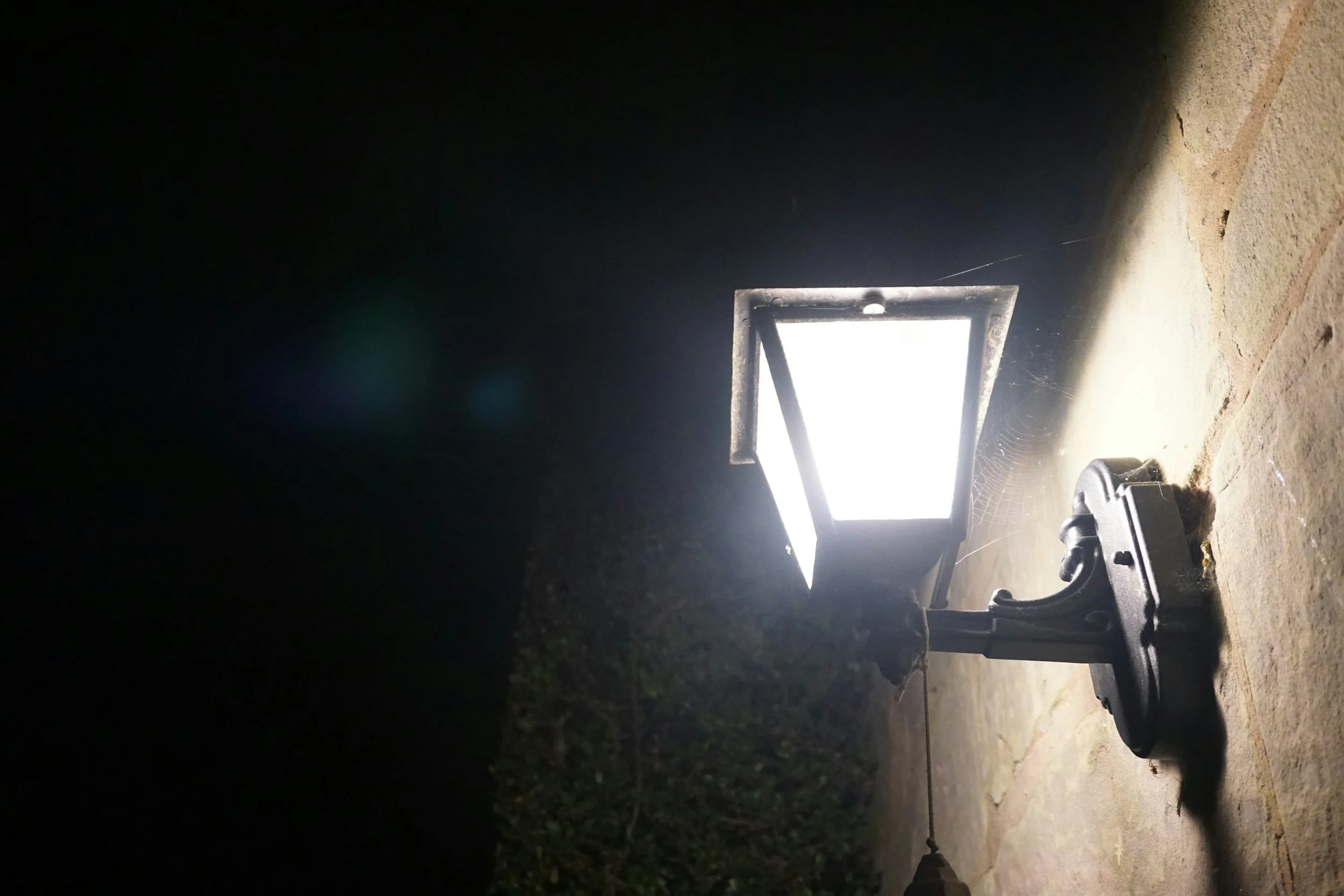 Outdoor solar-powered LED floodlight on a concrete surface at night, casting bright light with a dark background.