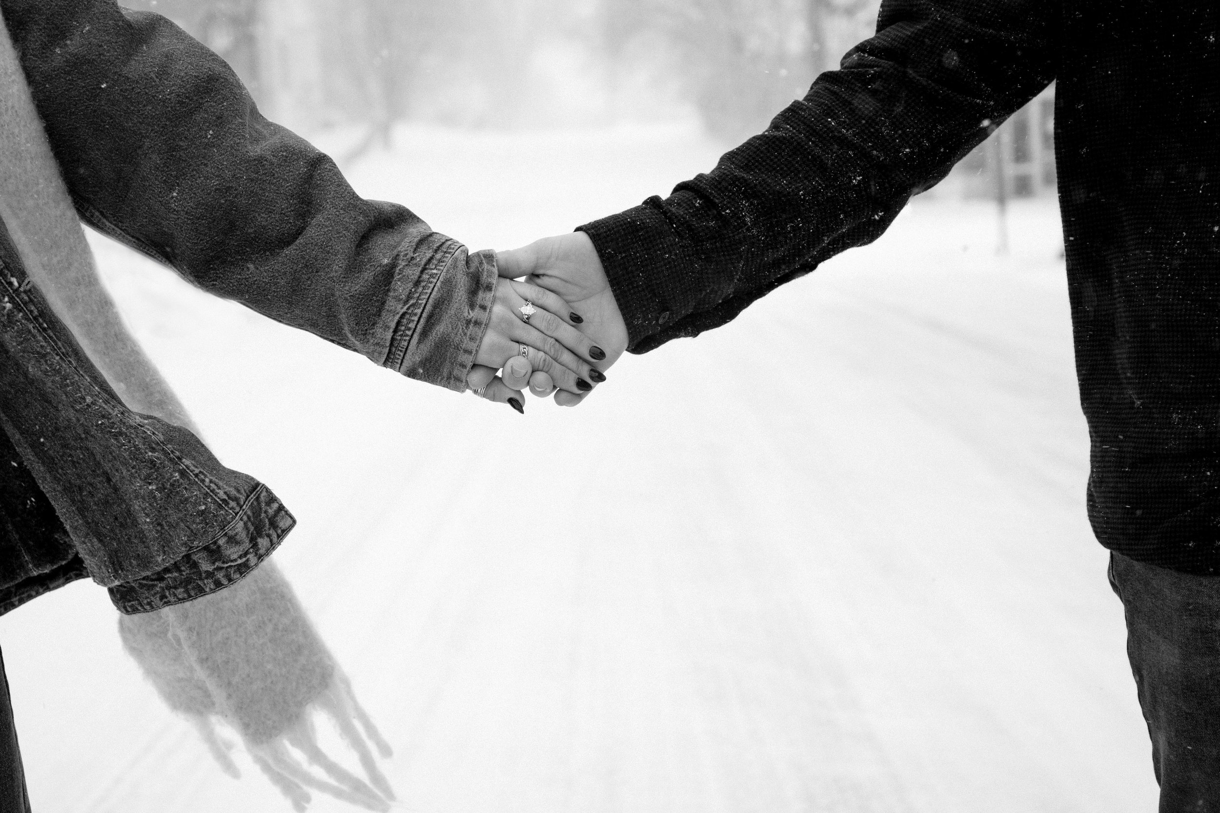 Two people holding hands outdoors in the snow.