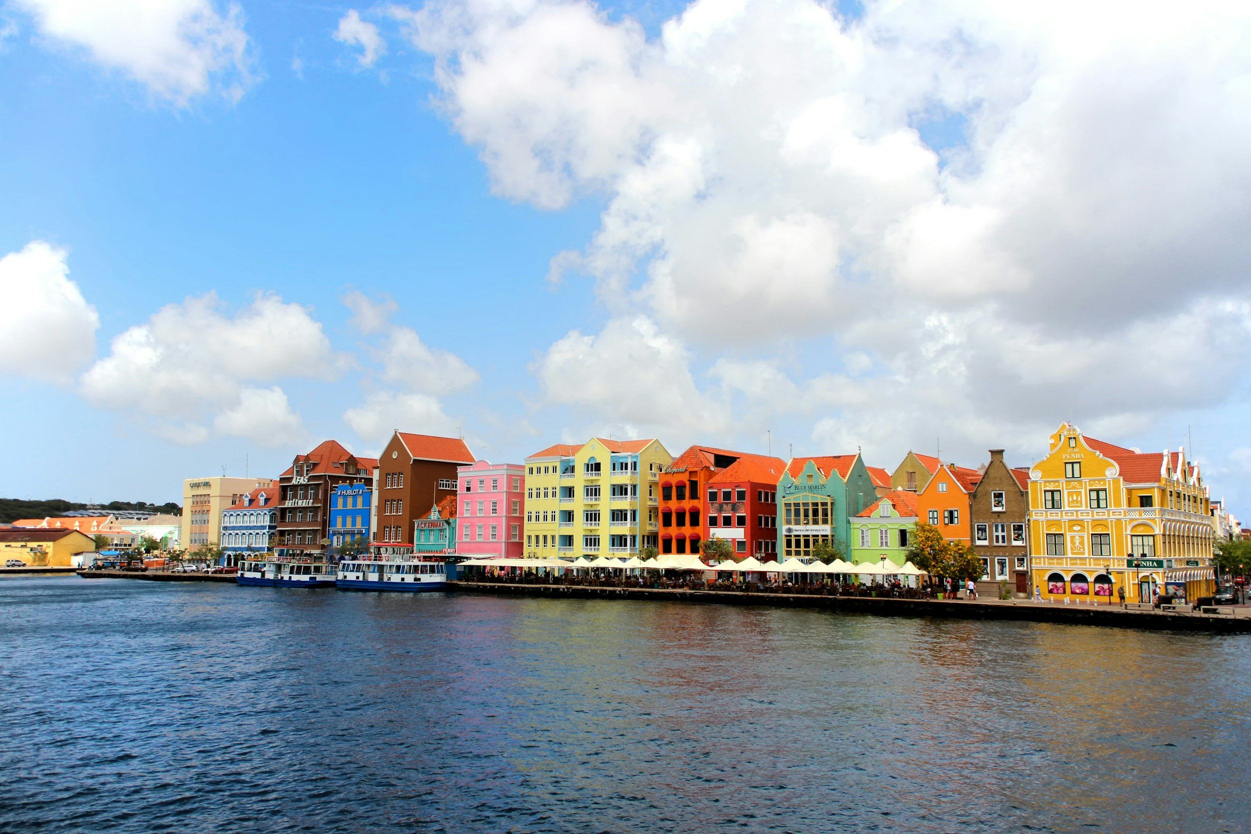 Colorful European-style buildings along a canal under a partly cloudy sky.