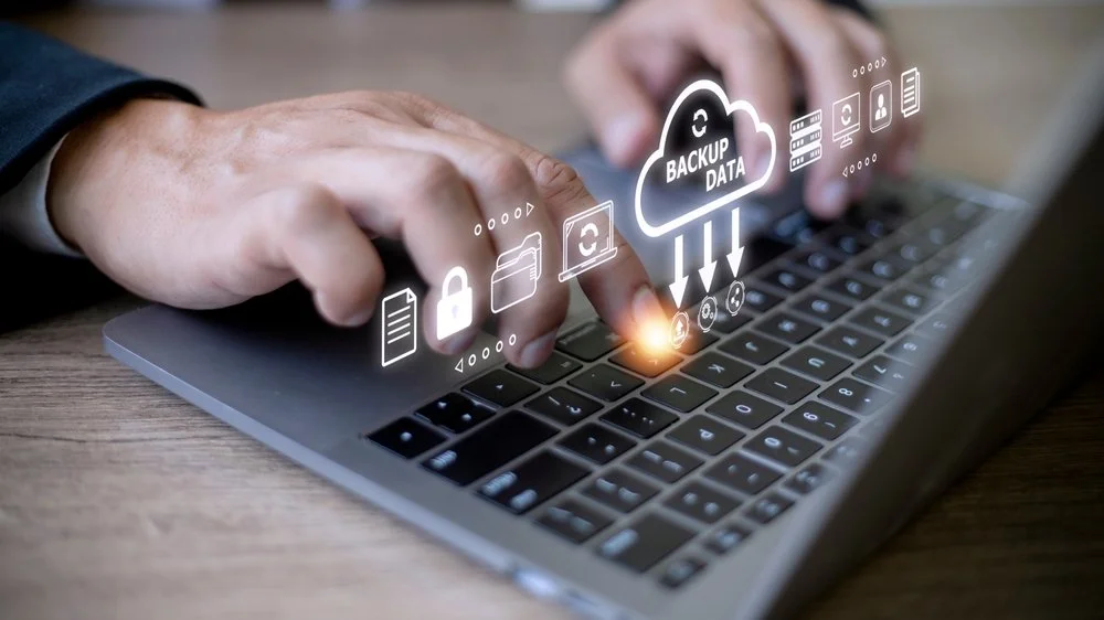 Small business owner reviewing a data backup and recovery service dashboard showing automated backup status and recovery options