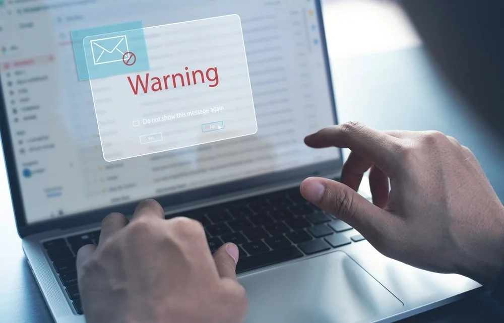 Person using a laptop that has triggered a security warning after encountering phishing email examples designed to steal credentials
