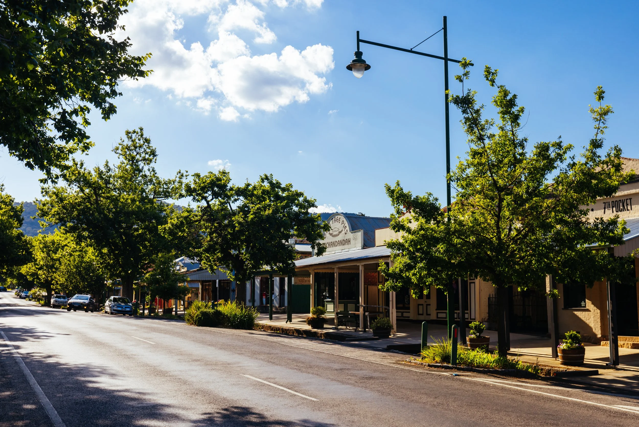 A tree-lined main street with heritage shopfronts and shaded verandahs reflects small-town charm, local enterprise and a welcoming regional community.