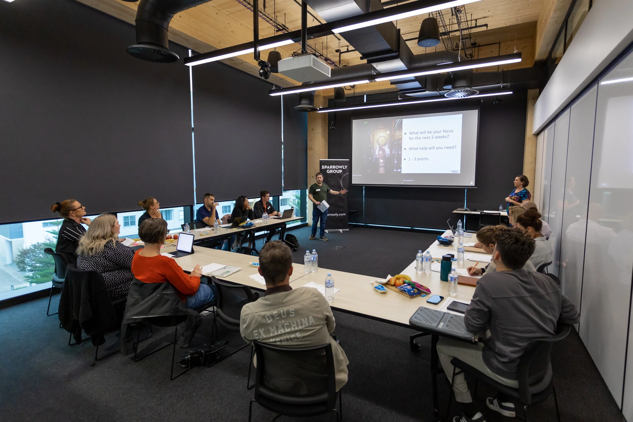 A presenter leads a professional workshop session, engaging participants in discussion.