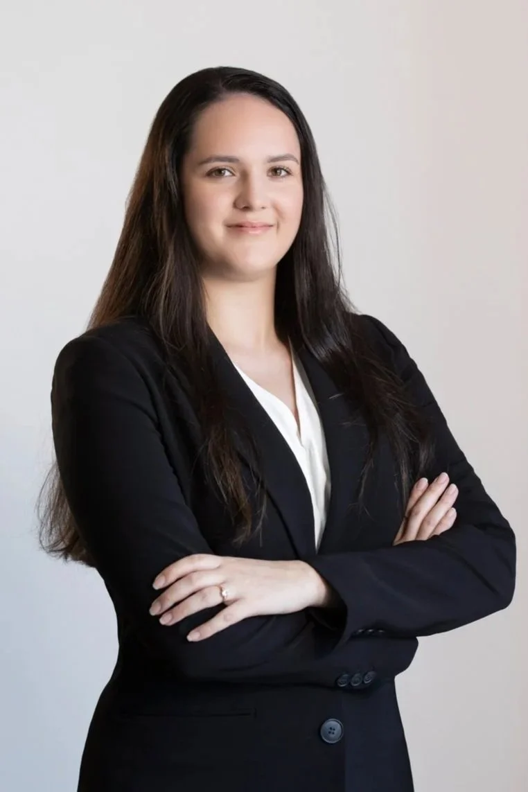 Portrait of Morgan Chong with arms crossed, wearing a black blazer over a white top against a light neutral background.