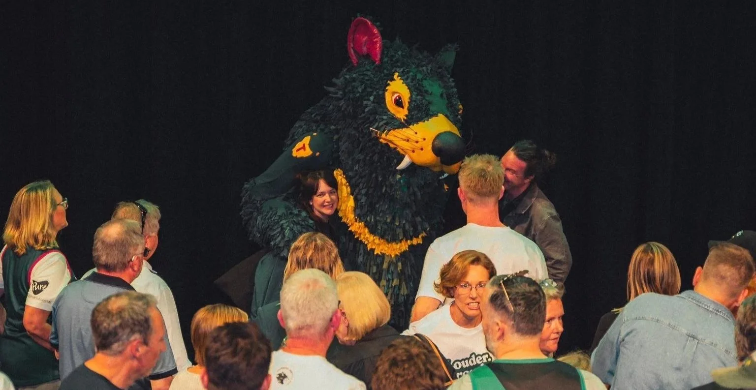 Tasmania Devils AFL mascot Rum’un interacting with a crowd of male and female supporters at a community event, celebrating club pride and connection.