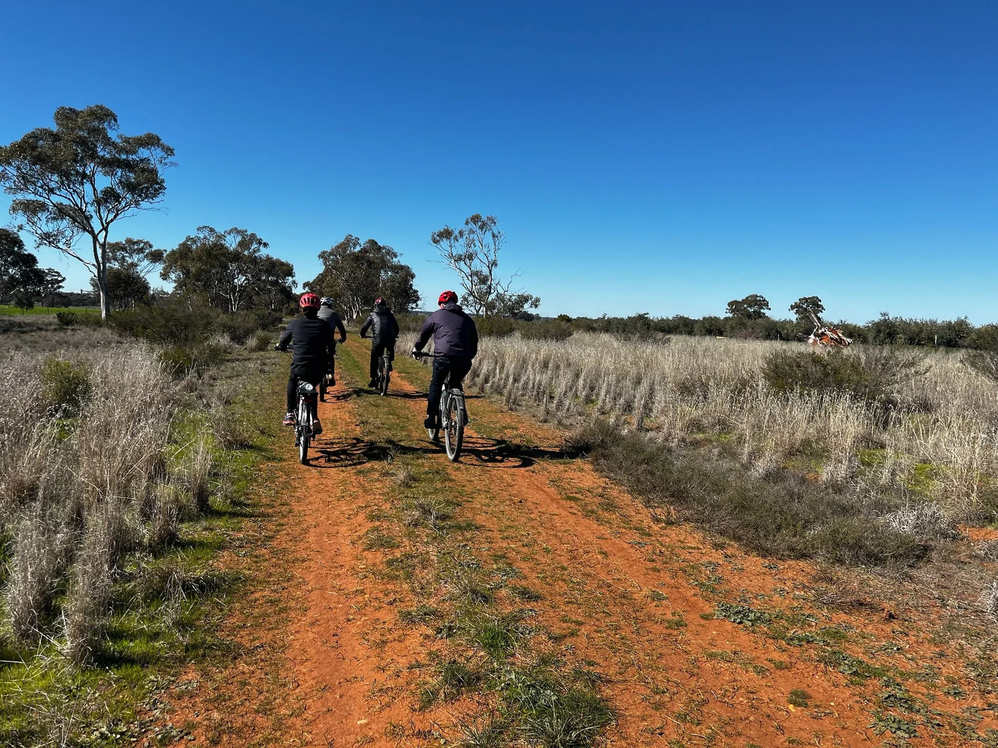 Cyclists ride along a rural trail through open countryside, reflecting active tourism, wellbeing and connection with nature.