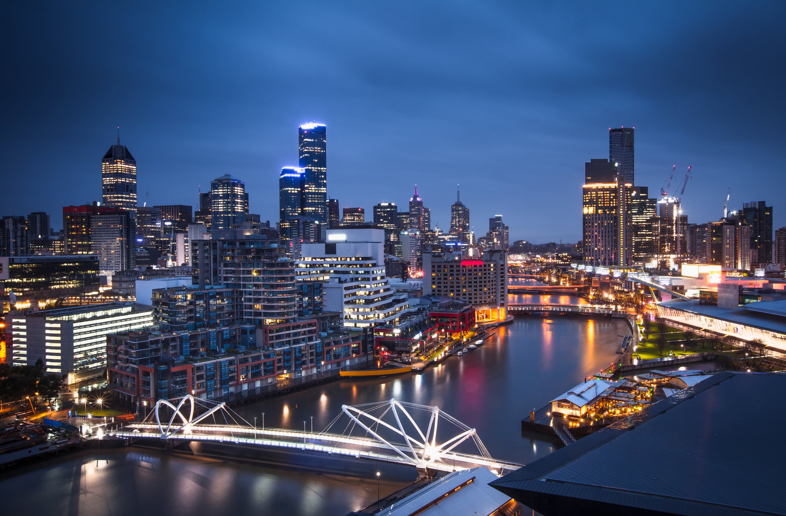 A night time aerial view of Melbourne city with bright lights.