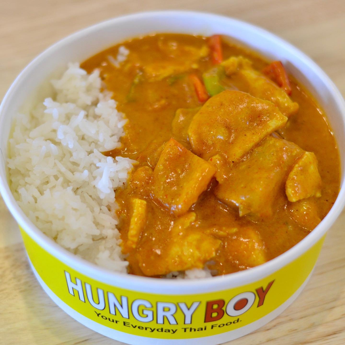 A bowl of Thai curry with chicken and vegetables served with white rice, in a colorful Hungry Boy bowl.
