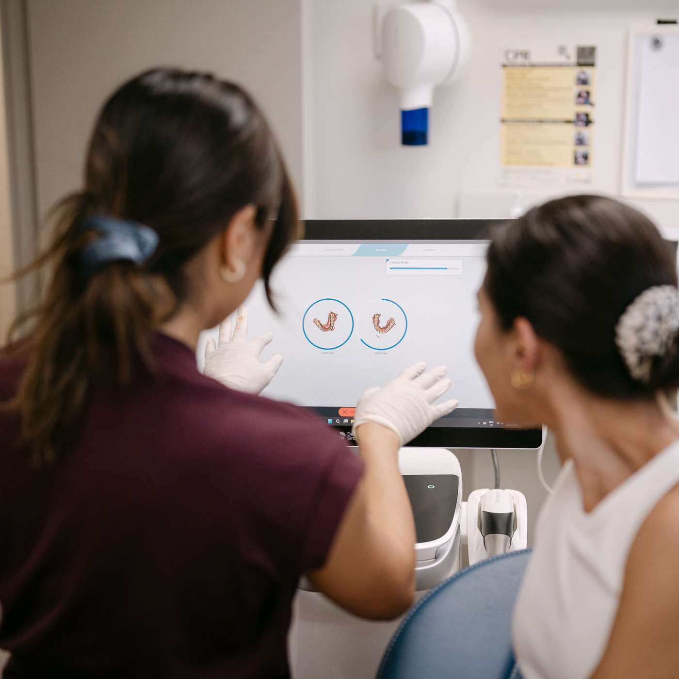 Medical professionals examining 3D models of human teeth on a computer screen.