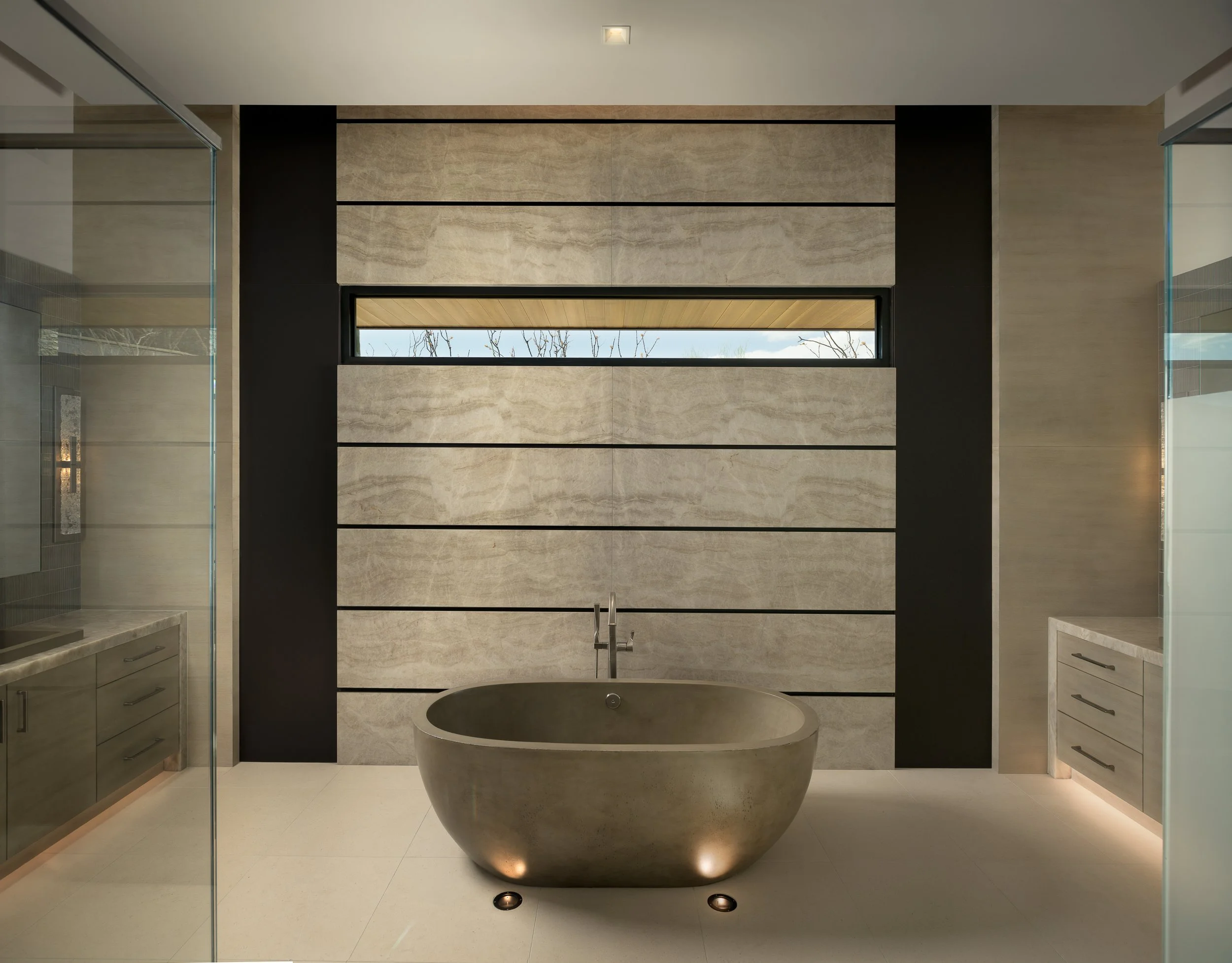 Bathroom concrete bathtub stone wall panels metal details: Custom Taj Mahal wall panels with inset metal border. Concrete freestanding bath with tub filler. 