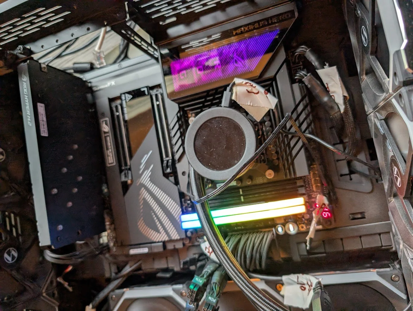 The inside of a computer case showing a motherboard, RAM sticks with RGB lighting, a CPU cooler, and various cables connected.
