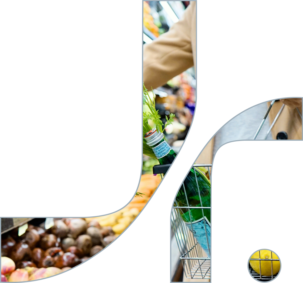 Partial view of a shopping cart filled with green bottles, a lemon on a black and yellow striped surface, and a person reaching for fruit at a grocery store. At a grocery store shopping, and the background shows fruits and vegetables.