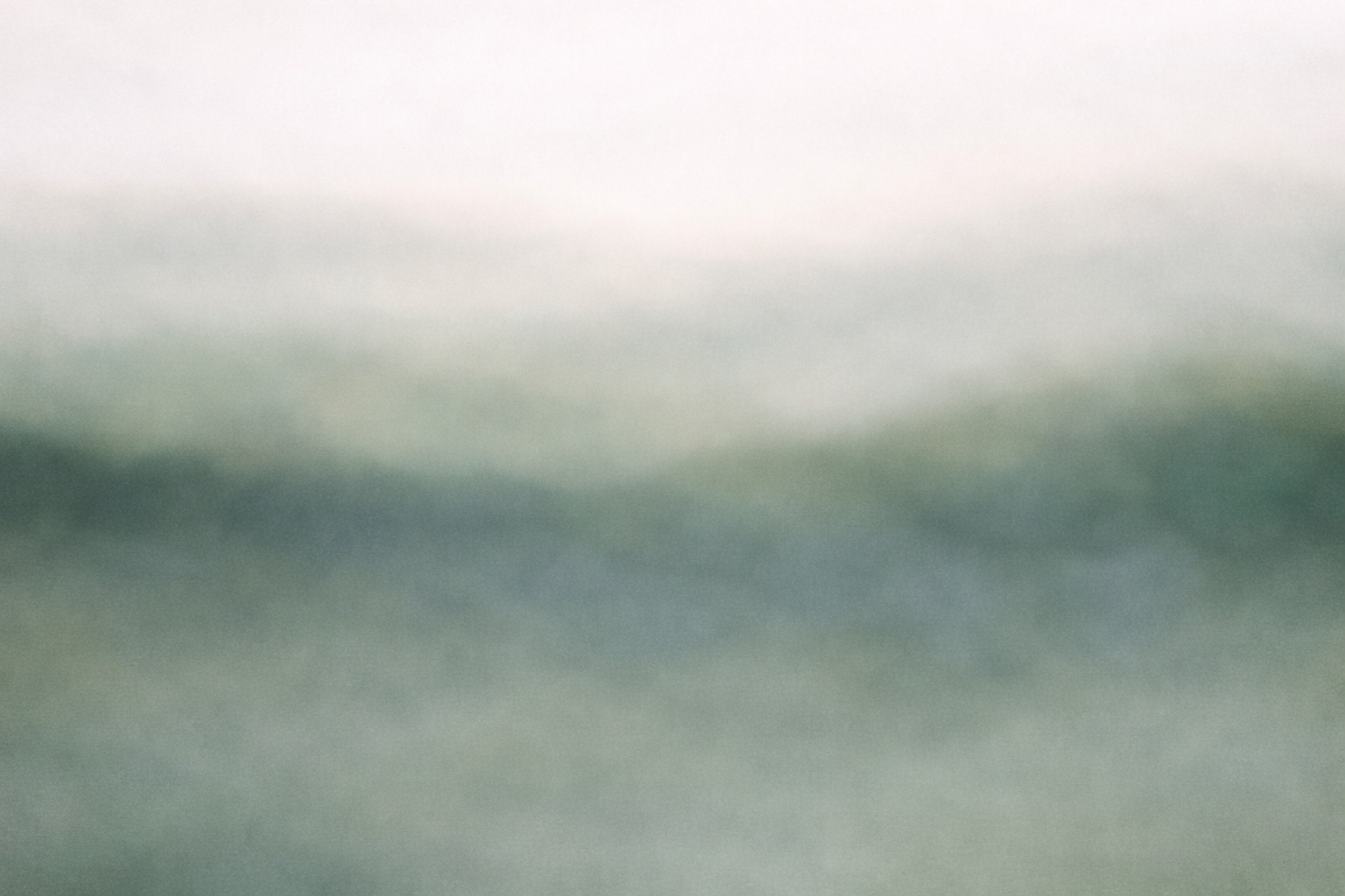 An abstract, blurred image with soft green and gray tones.