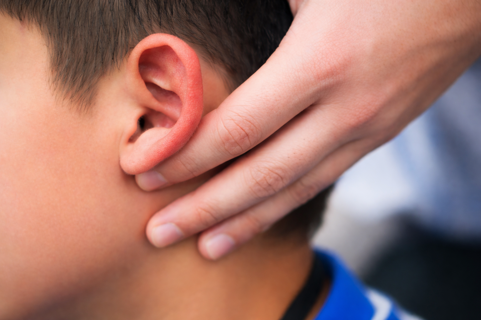 A person holding their hand to their ear, with the side of their face and ear visible in close-up.