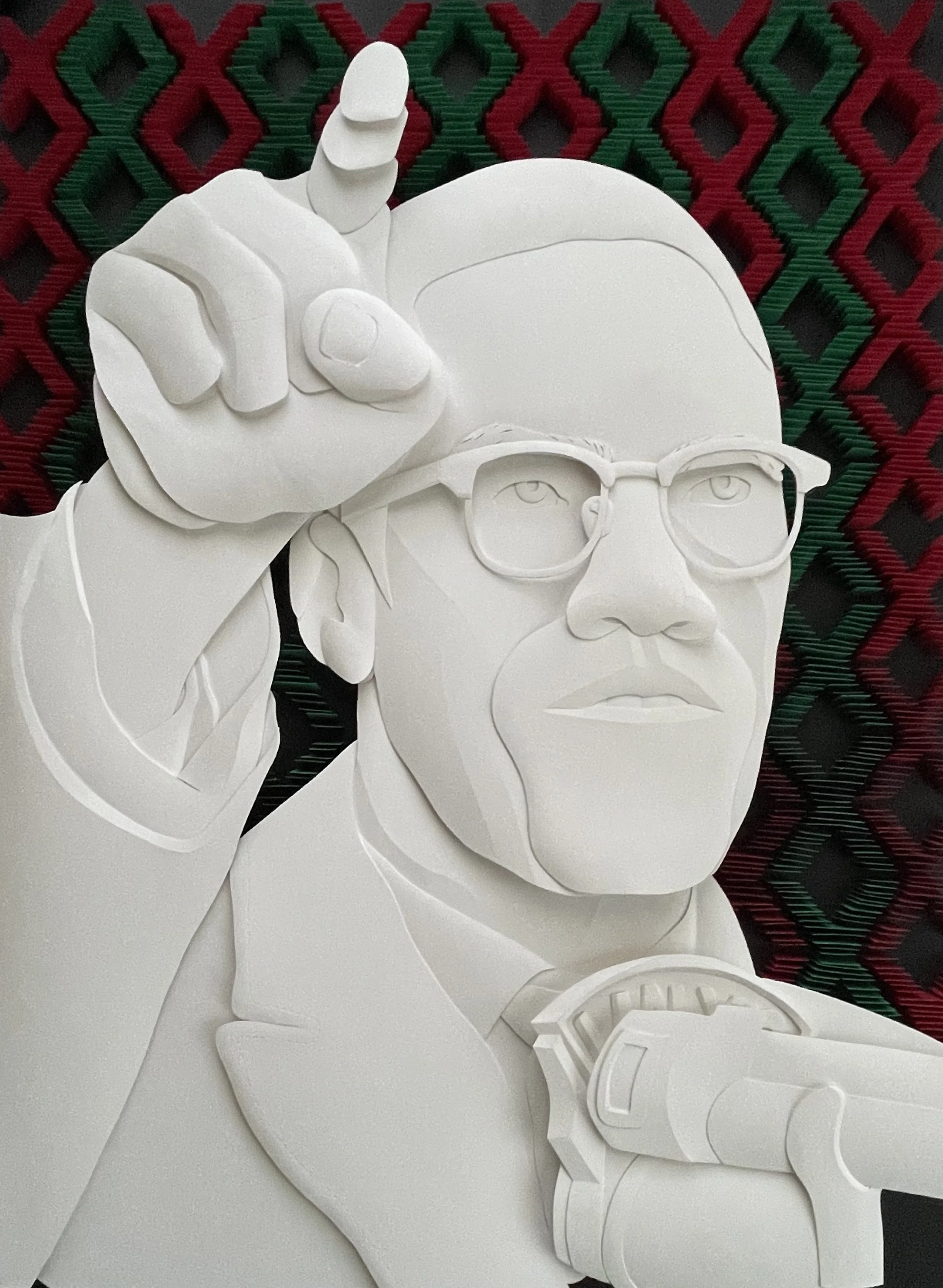 Paper sculpture of Malcolm X during a speech with finger pointing to the sky.