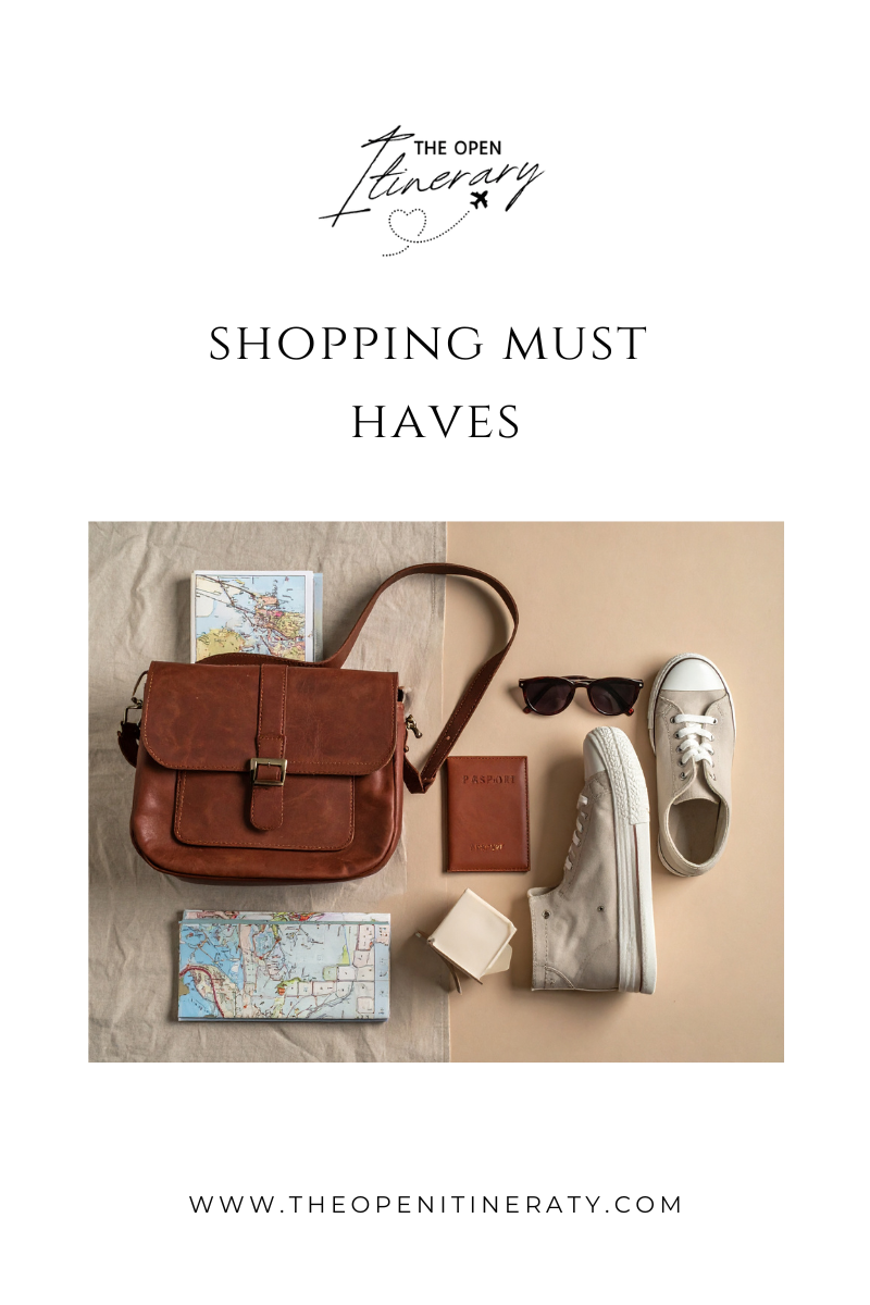 Travel essentials including a brown leather bag, a passport holder, sunglasses, a pair of white sneakers, a map, and a candle on a split beige and tan background.