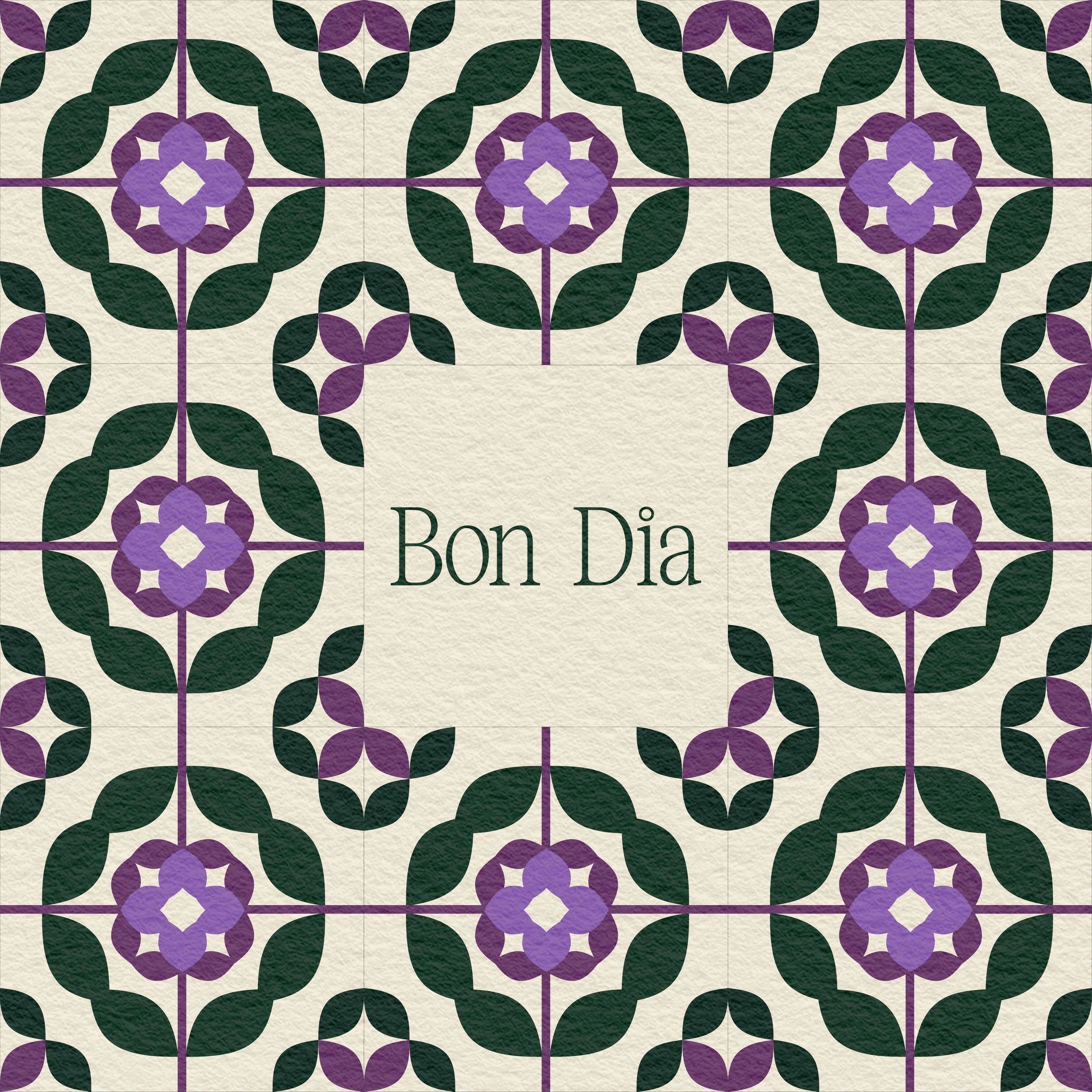 A decorative tile pattern featuring purple flowers, green leaves, and purple stems on a beige background. In the center, there is a white square with the words 'Bon Dia' written in green.